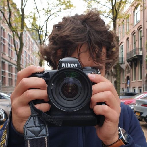 Portrait de Luca Defarges, photographe à Toulouse, tenant un appareil photo masquant son visage